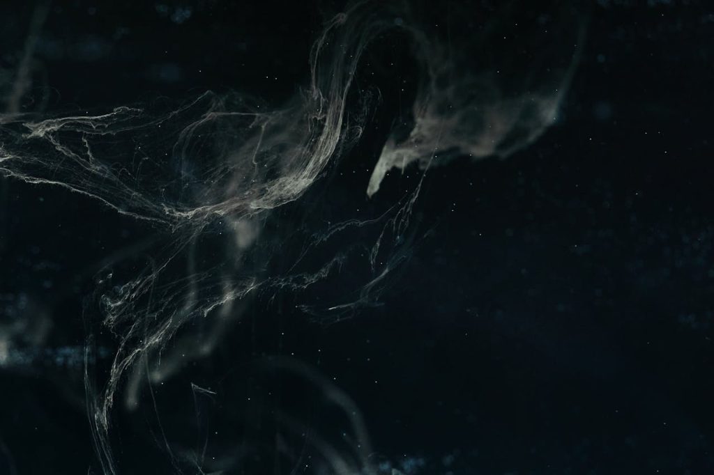 white-ink-diffusion-in-water-9668535 Abstract dark nebula image with swirling patterns and ethereal textures creating a cosmic feel.